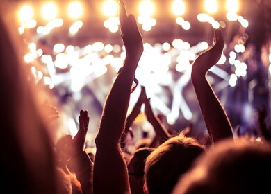 Eine Menge Leute, die feiern und feiern mit den Händen in der Luft zu einem fantastischen Dance musik | © Gettyimages.com/bernardbodo