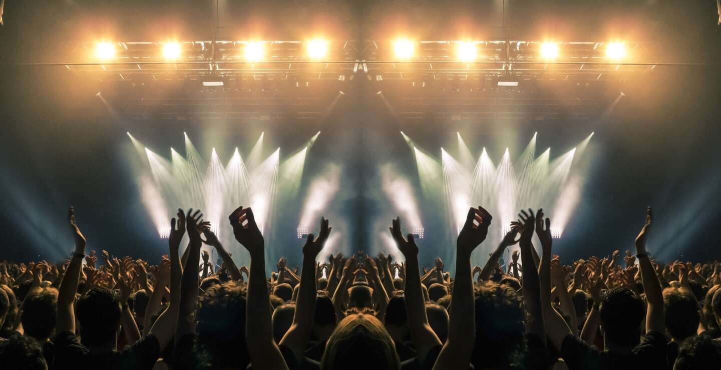 Konzertbuehne, Menschen winken und klatschen, Silhouetten sind sichtbar | © Gettyimages.com/cesareferrari