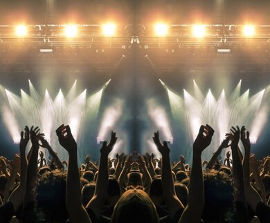 Konzertbuehne, Menschen winken und klatschen, Silhouetten sind sichtbar | © Gettyimages.com/cesareferrari