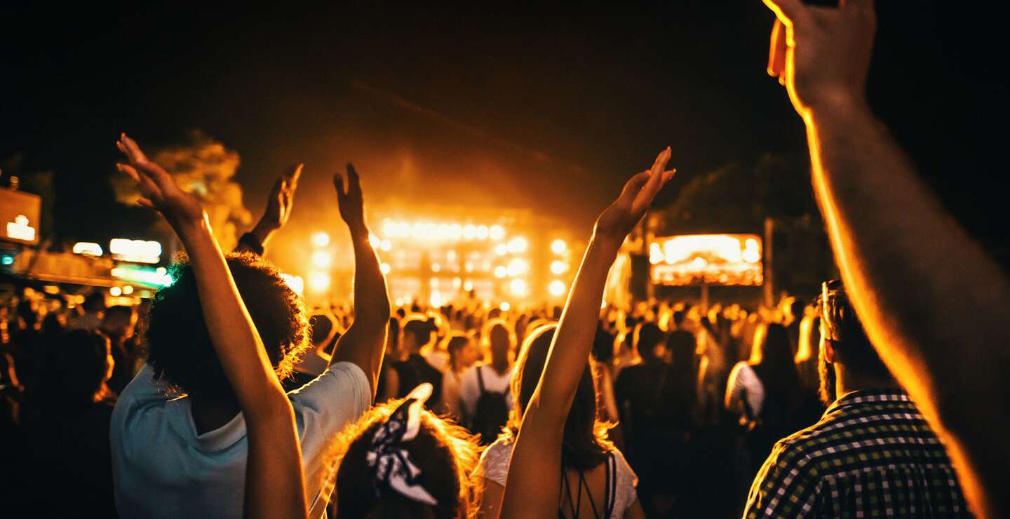 Rueckansicht einer grossen Gruppe von Menschen, die eine Konzertauffuehrung geniessen | © Gettyimages.com/gilaxia