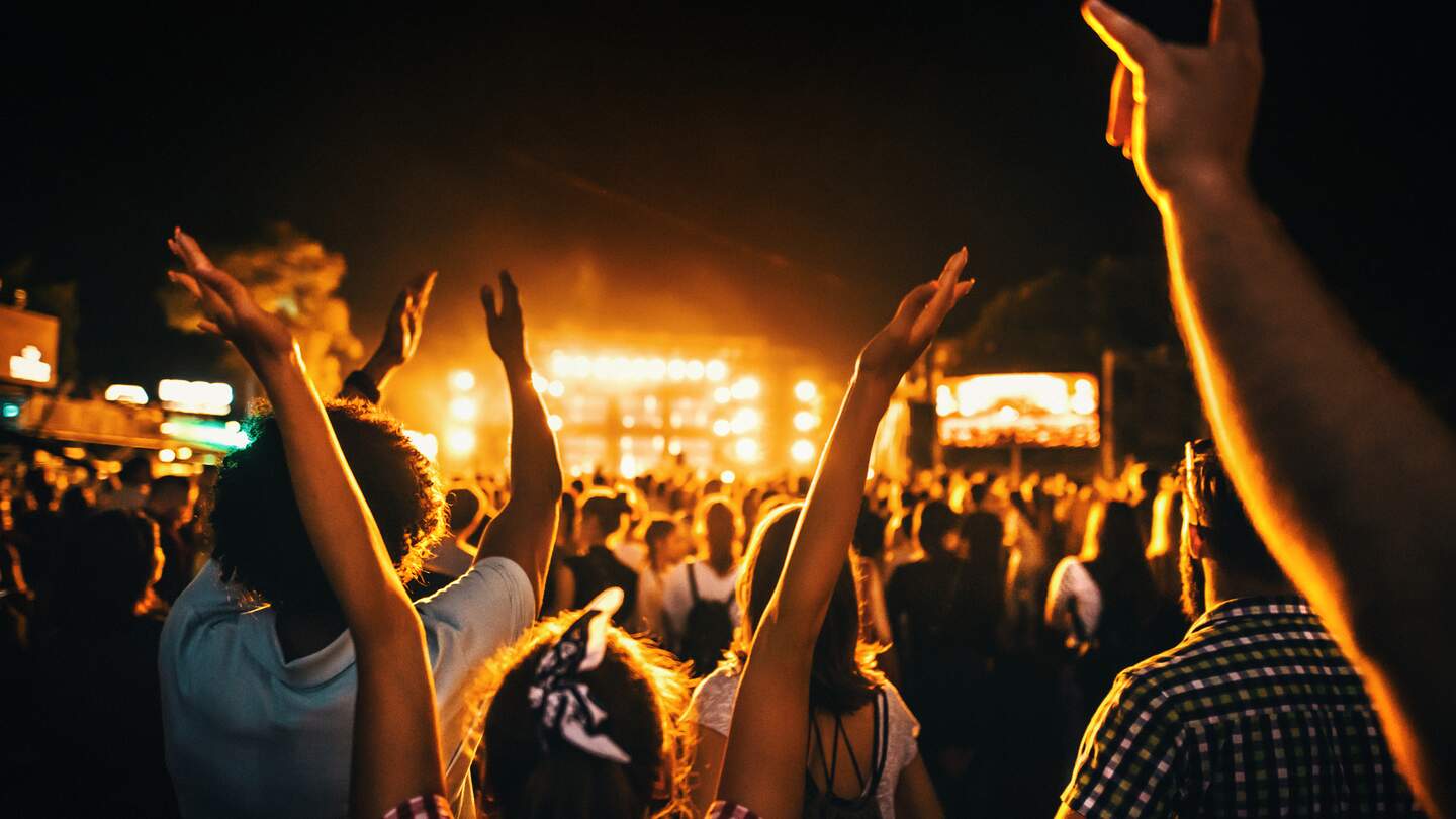 Rueckansicht einer grossen Gruppe von Menschen, die eine Konzertauffuehrung geniessen | © Gettyimages.com/gilaxia