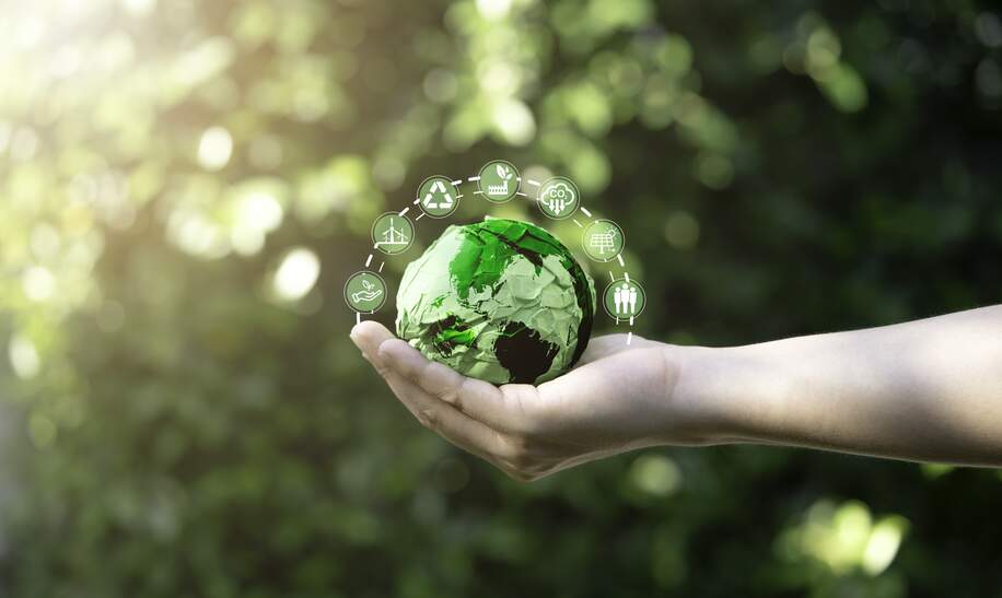 Mann hält grüne Erde mit Emojis drum herum | © Gettyimages.com/DilokKlaisataporn