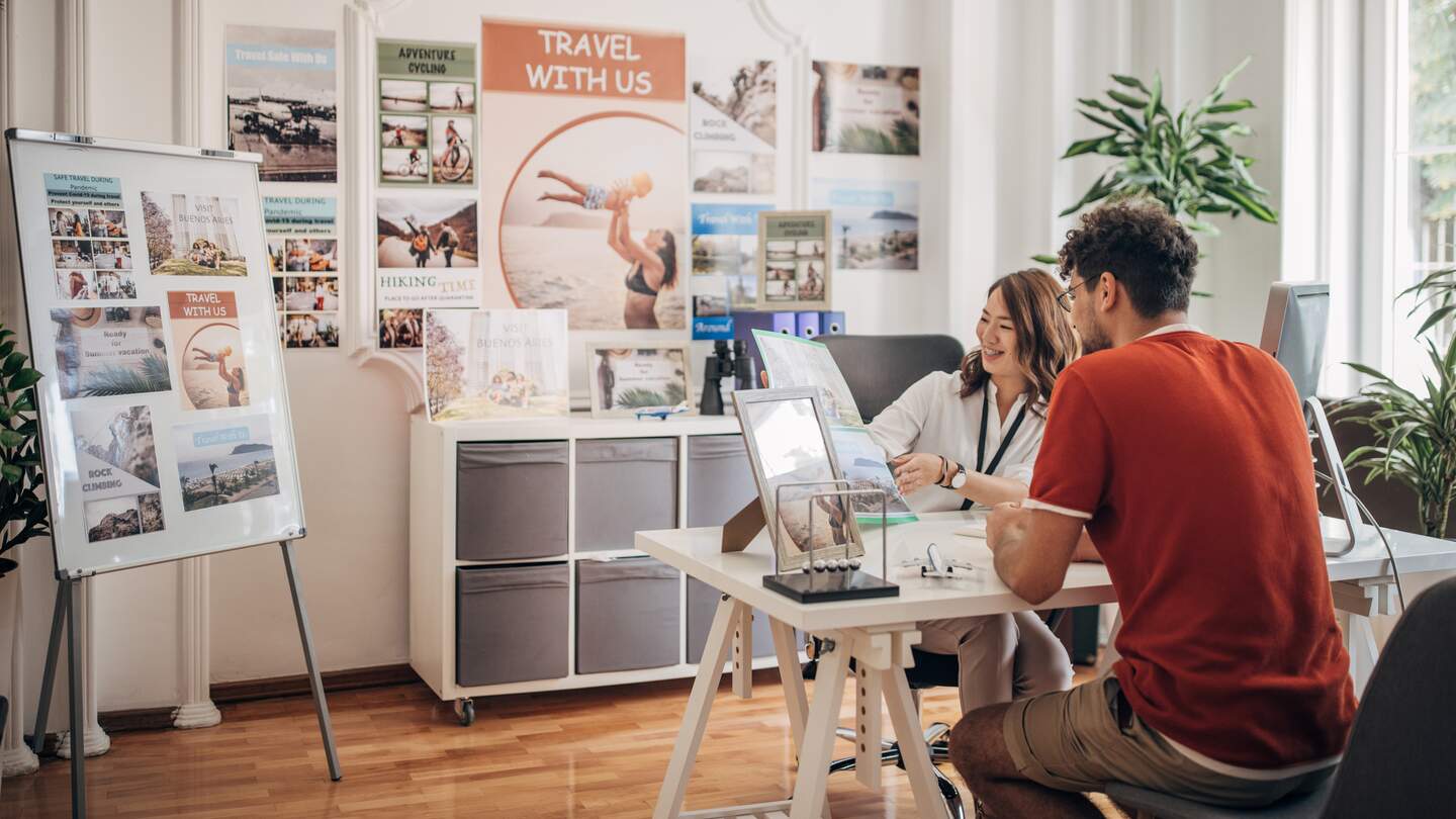 Mann und Frau planen eine Reise am Tisch im Reisebüro | © Gettyimages.com/South_agency