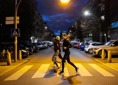 Drei Menschen joggen ueber einen Zebrastreifen. Es ist Nacht. | © Gettyimages.com/alvarez