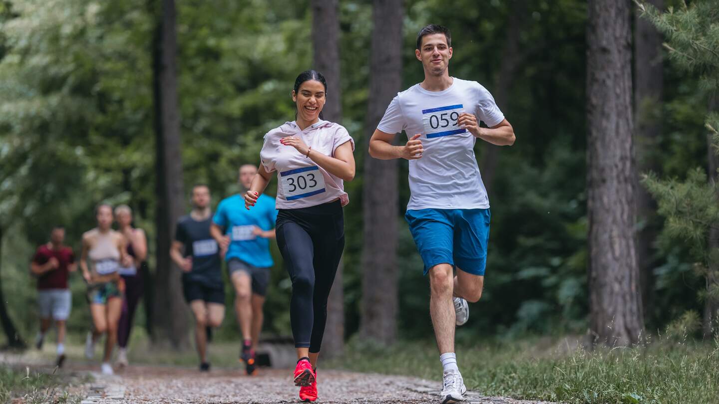 Gruppe von Freunden, die auf Marathon im Wald laufen | © Gettyimages.com/nenadstojnev