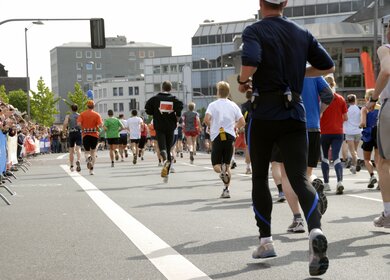 Laeufer laufen durch die Strassen einer Stadt, am Rande stehen Zuschauer | © Gettyimages.com/silviajansen