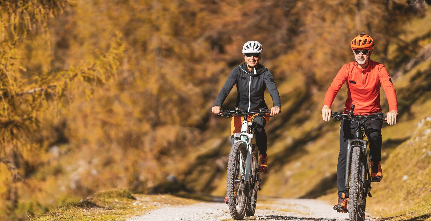 Paar auf einer Radtour auf einem Berg mit herbstlich gefaerbte laendliche Landschaft. | © Gettyimages.com/amriphoto