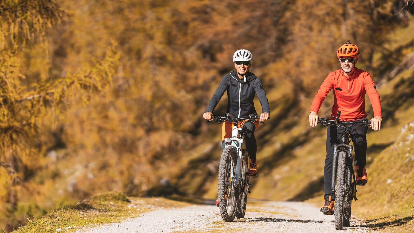 Paar auf einer Radtour auf einem Berg mit herbstlich gefaerbte laendliche Landschaft. | © Gettyimages.com/amriphoto