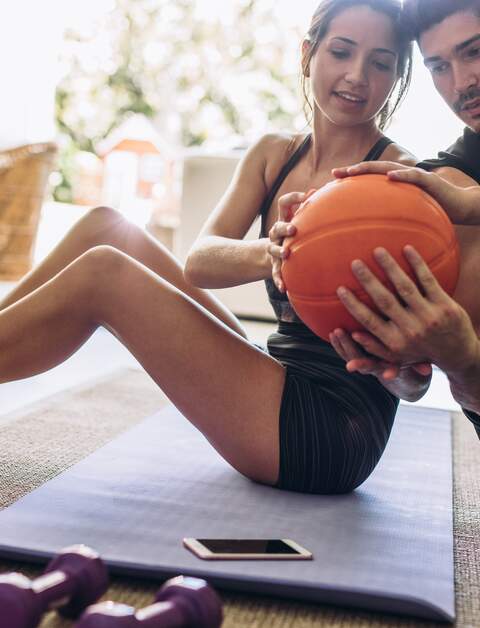 junges Paar, das zu Hause uebungen mit einem Ball macht | © gettyimages.com/jacoblund