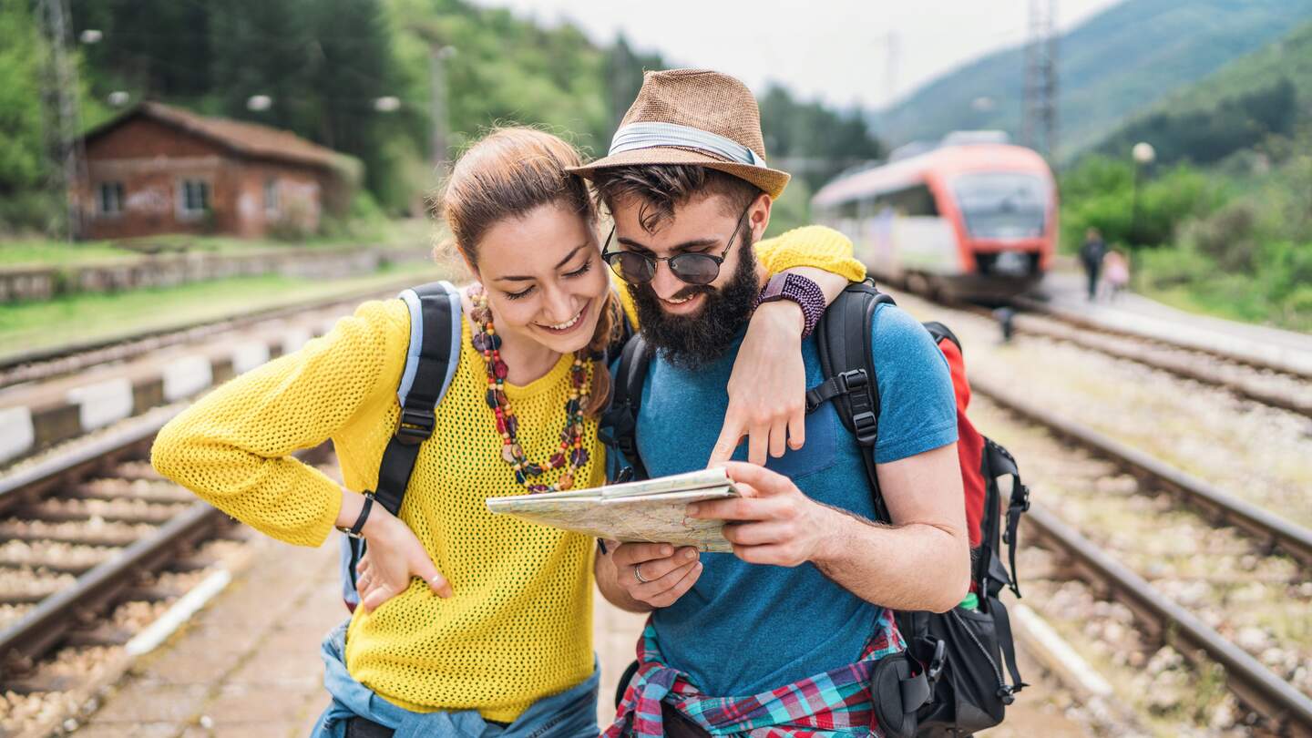 Junges Paar auf Bahn-Wanderreise schaut auf der Wanderkarte nach dem Weg | © GettyImages.com/	Mixmike