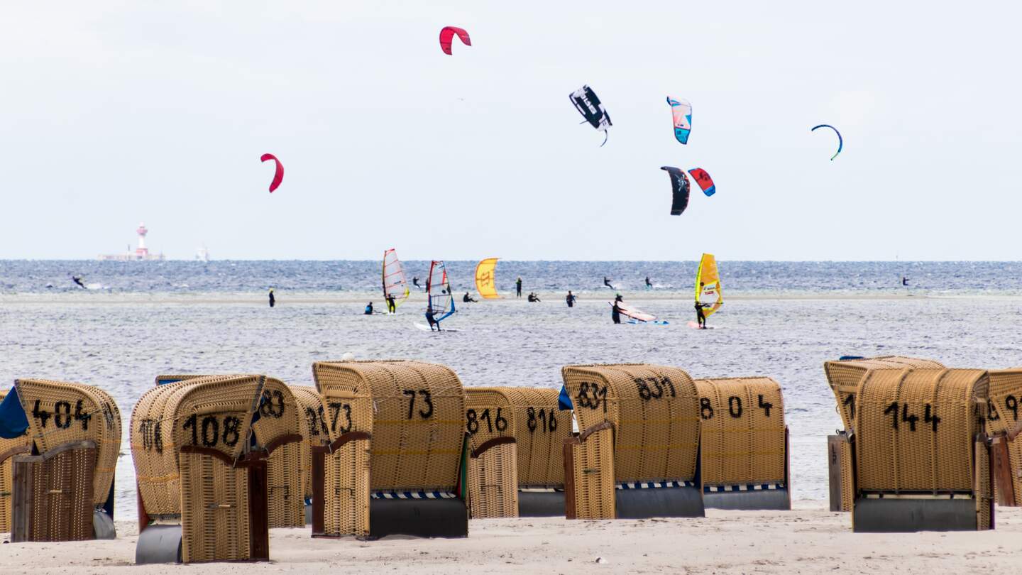 Wind- und Kitesurfer auf dem Wasser mit Strandkoerben im Vordergrund | © Gettyimages.com/Florian Graf