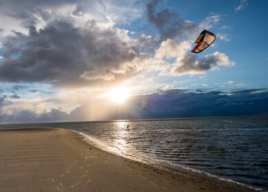  eine ruhige Strandszene mit einer einzelnen Person, die beim Kitesurfen ist. | © Gettyimages.com/Animaflora