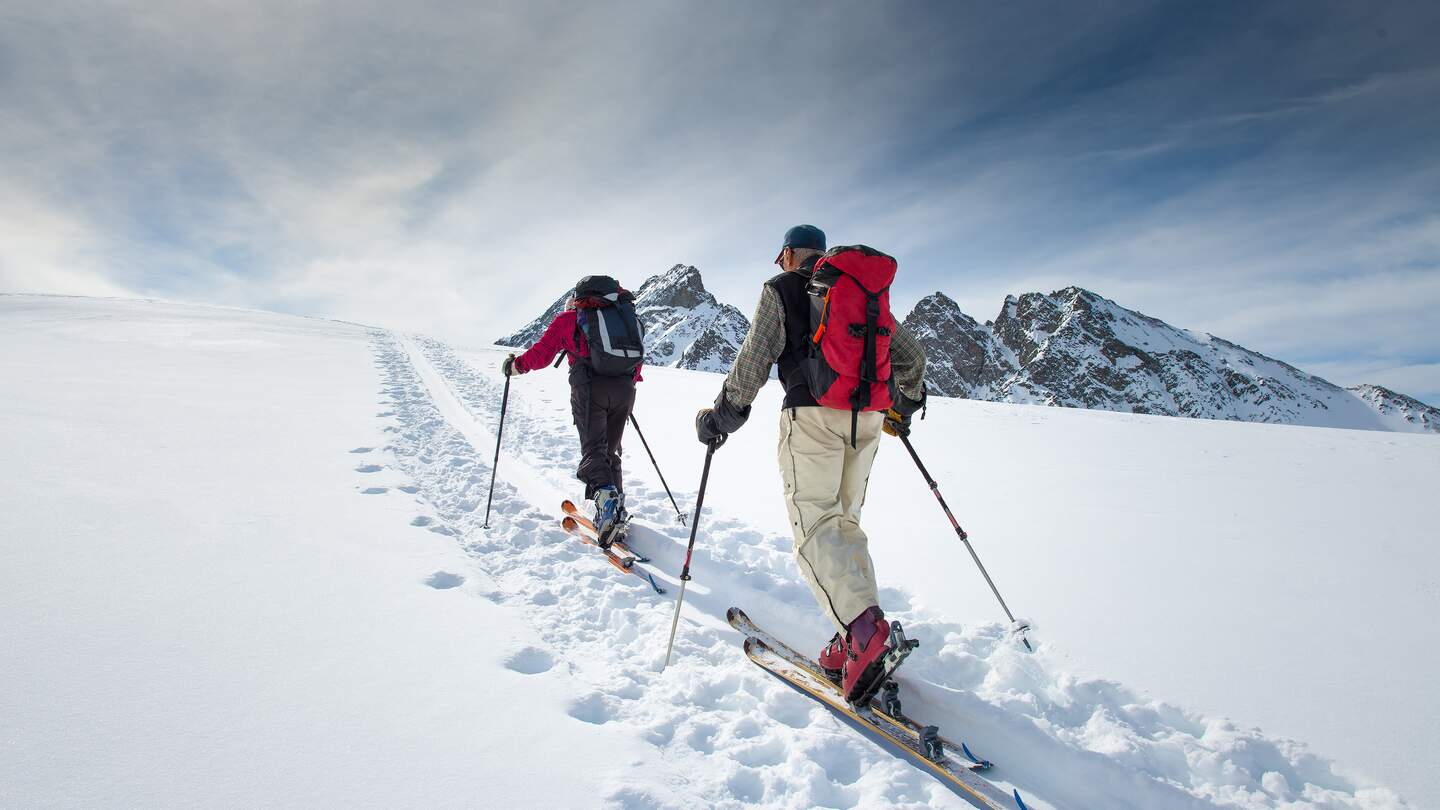 Zwei aeltere Alpinskifahrer steigen auf Skier  | © gettyimages.com/michelangeloop