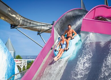 Pärchen auf der Big Wave Rutsche in der Therme Erding auf einem Schwimmreifen | © THERME ERDING