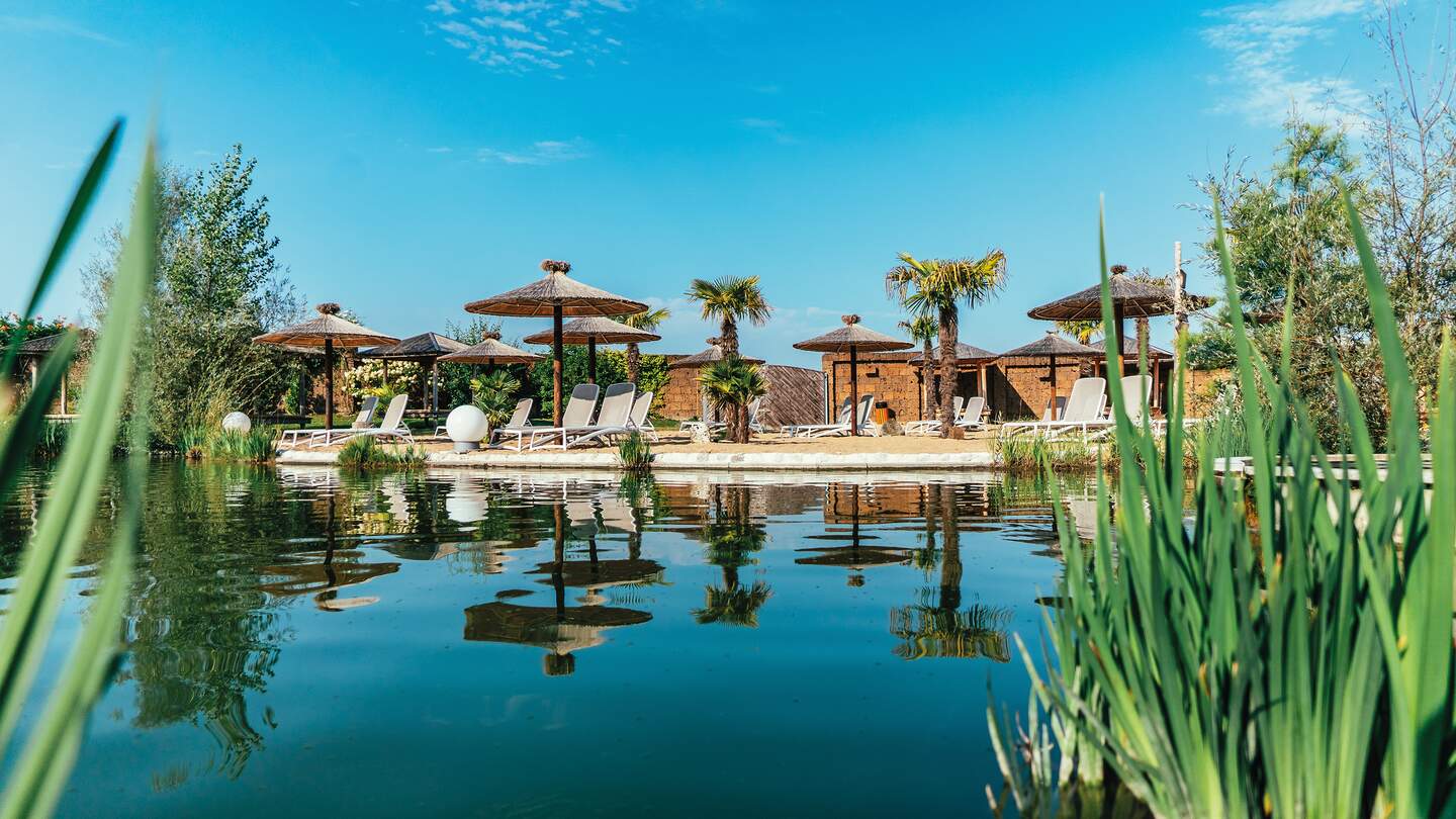Außenbereich mit See, Liegen, Sonnenschirmen und Sandstrand | © Ariel Spallek