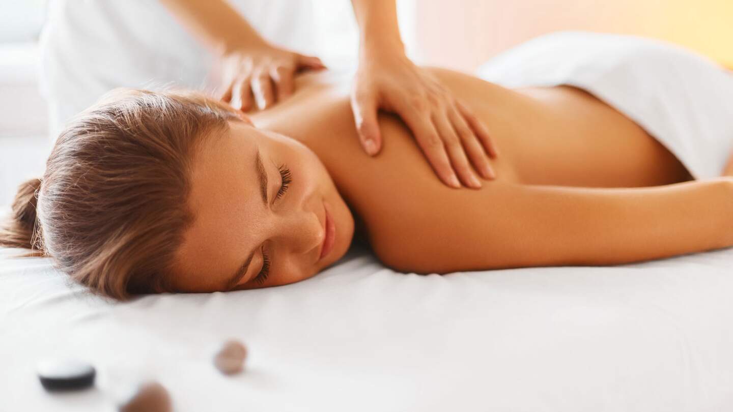 Frau genießt entspannende Rückenmassage im Kosmetik-Spa-Center | © Gettyimages.com/puhhha