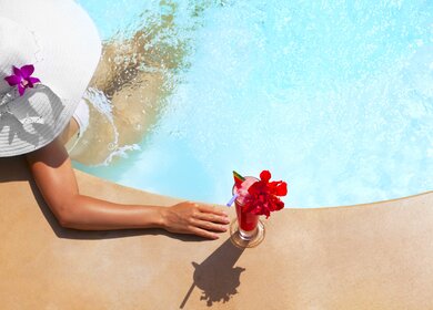 Aufsicht auf eine Frau, die ihren Wellness im Pool mit einem Cocktail geiesst | © Gettyimages.com/VladGans