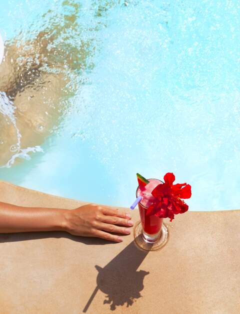 Aufsicht auf eine Frau, die ihren Wellness im Pool mit einem Cocktail geiesst | © Gettyimages.com/VladGans