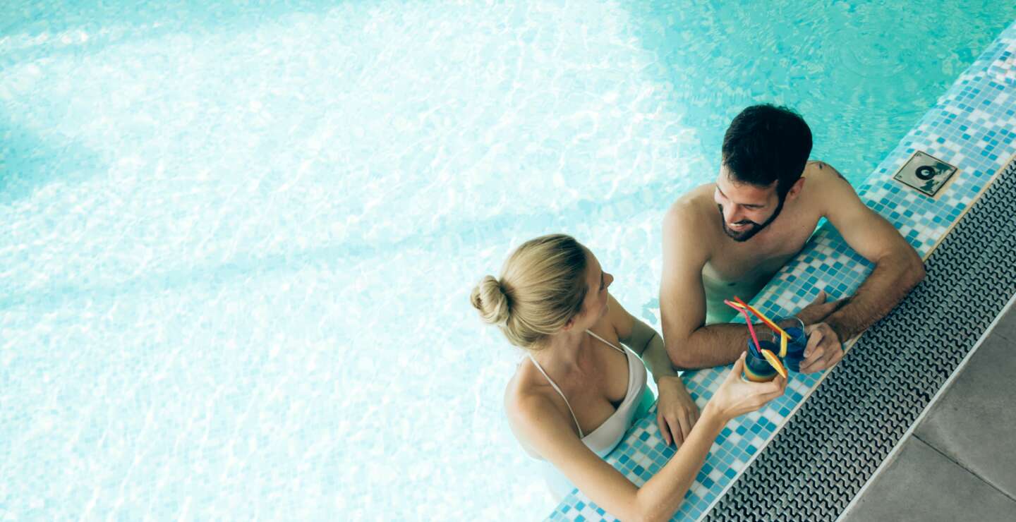 Aufsicht auf ein Paar, dass sich im Pool mit Cocktails entspannt | © Gettyimages.com/nd3000