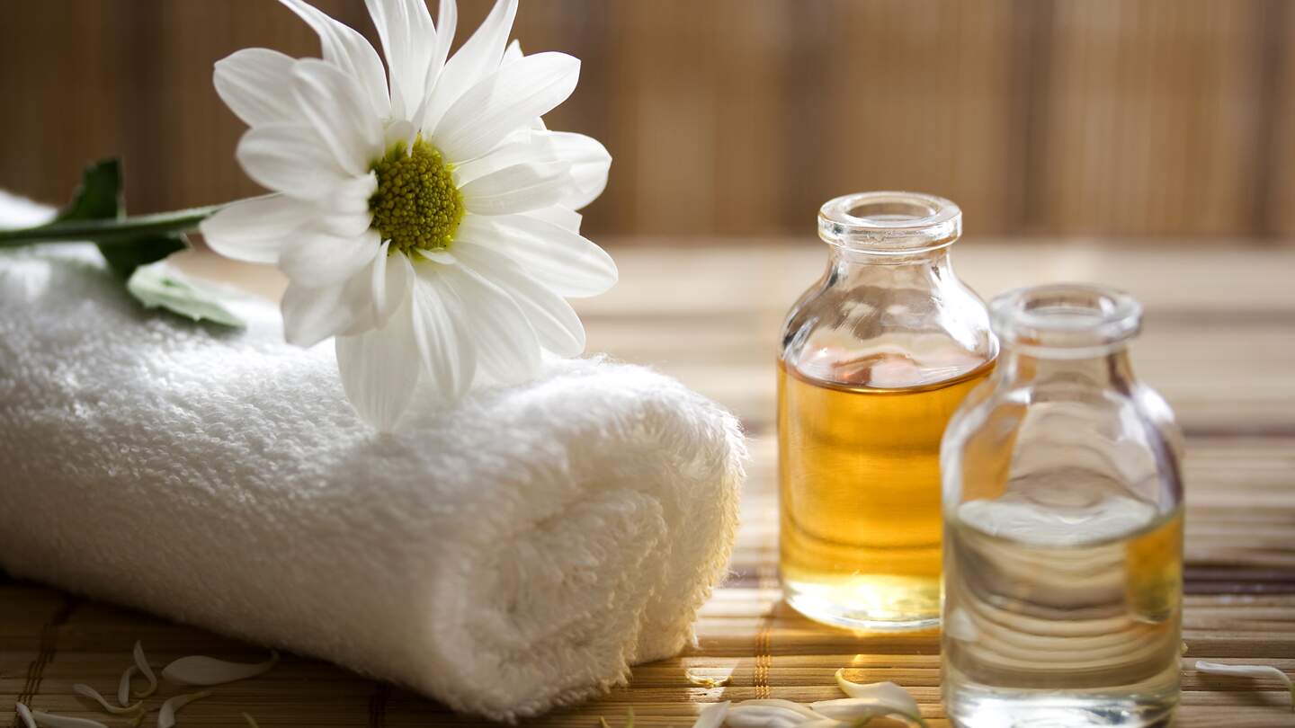 Essenzen fuer die Aroma-Therapie mit Handtuch und Blume | © Gettyimages.com/damircudic