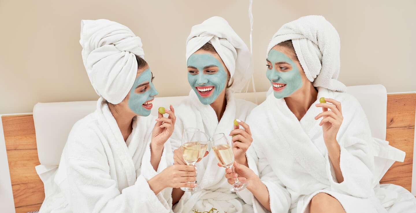 Vorderansicht einer Gruppe von Maedchen mit kosmetischen Masken, in Handtuechern und Bademaenteln | © Gettyimages.com/SerhiiBobyk