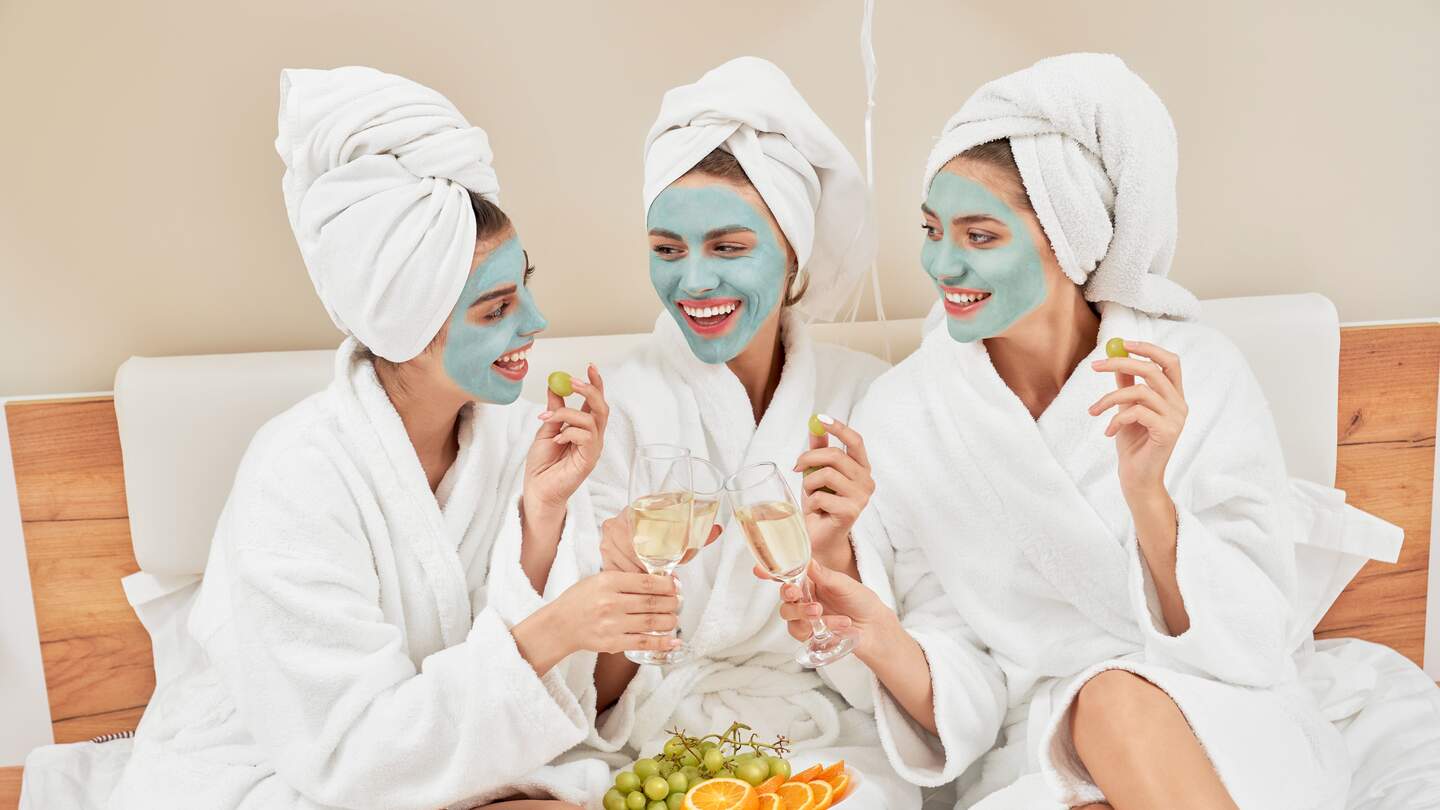 Vorderansicht einer Gruppe von Maedchen mit kosmetischen Masken, in Handtuechern und Bademaenteln | © Gettyimages.com/SerhiiBobyk