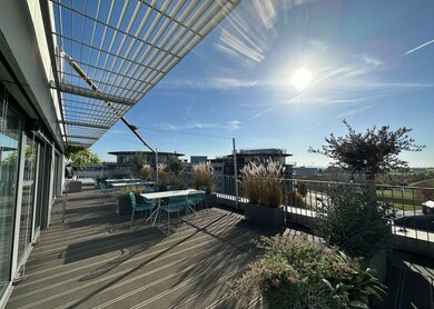 Die begrünte Ameropa-Terrasse mit Sonnensegel und Skylineblick an einem schönen Sommertag | © Ameropa/Verena Cezanne