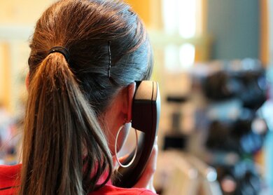 Hinterkopf einer Frau mit Zopf und altem Kabeltelefon am Ohr | © Pixabay.com/guvo59