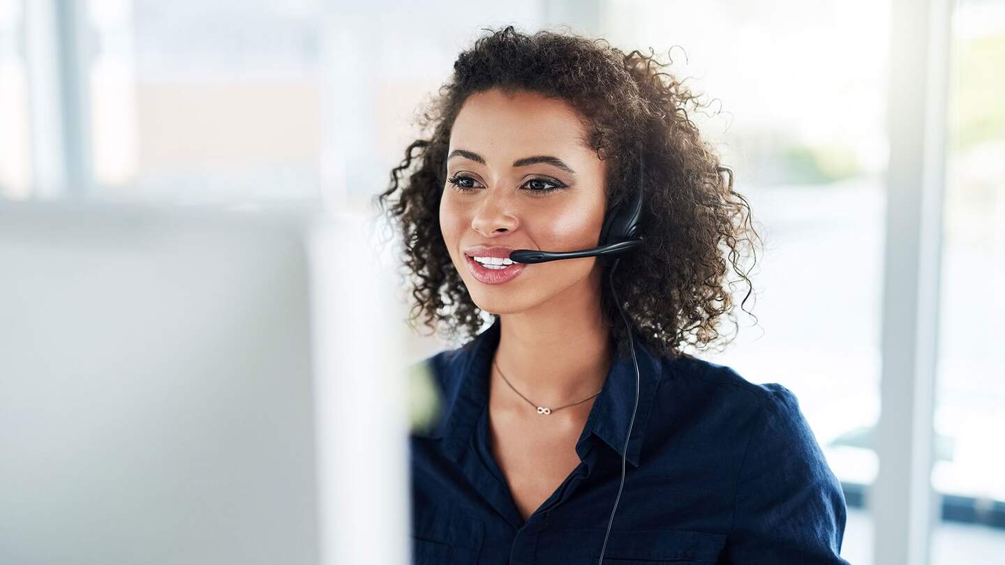 Ausschnitt einer attraktiven jungen Callcenter-Agentin bei der Arbeit in ihrem Buero | © Gettyimages.com/peopleimages