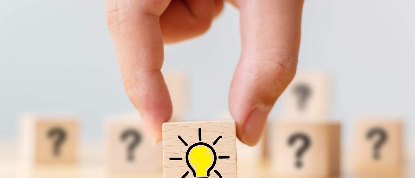 Handverlesener Holzwuerfel mit Fragezeichen Symbol und Gluehbirnensymbol | © Gettyimages.com/marchmeena29