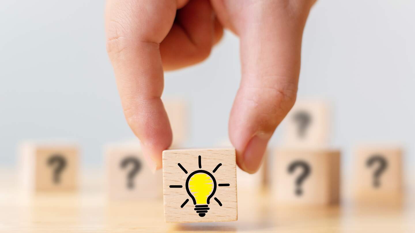 Handverlesener Holzwuerfel mit Fragezeichen Symbol und Gluehbirnensymbol | © Gettyimages.com/marchmeena29