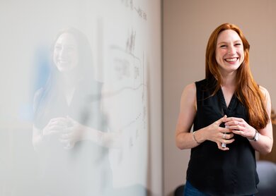 Rothaarige Frau steht laechelnd neben einer weissen Tafel mit Skizzen | © Pixabay/RAEng_Publications