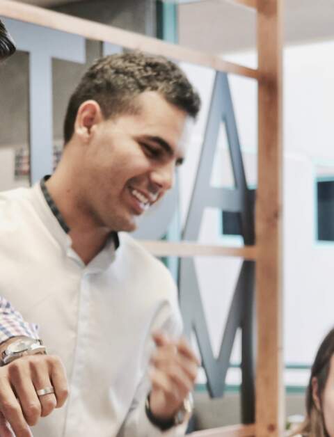 Eine Frau sitzt am Tisch vor einem Laptop, drei weitere Personen stehen neben ihr und schauen auf einen anderen Laptop | © Pixabay/CampaignCreators