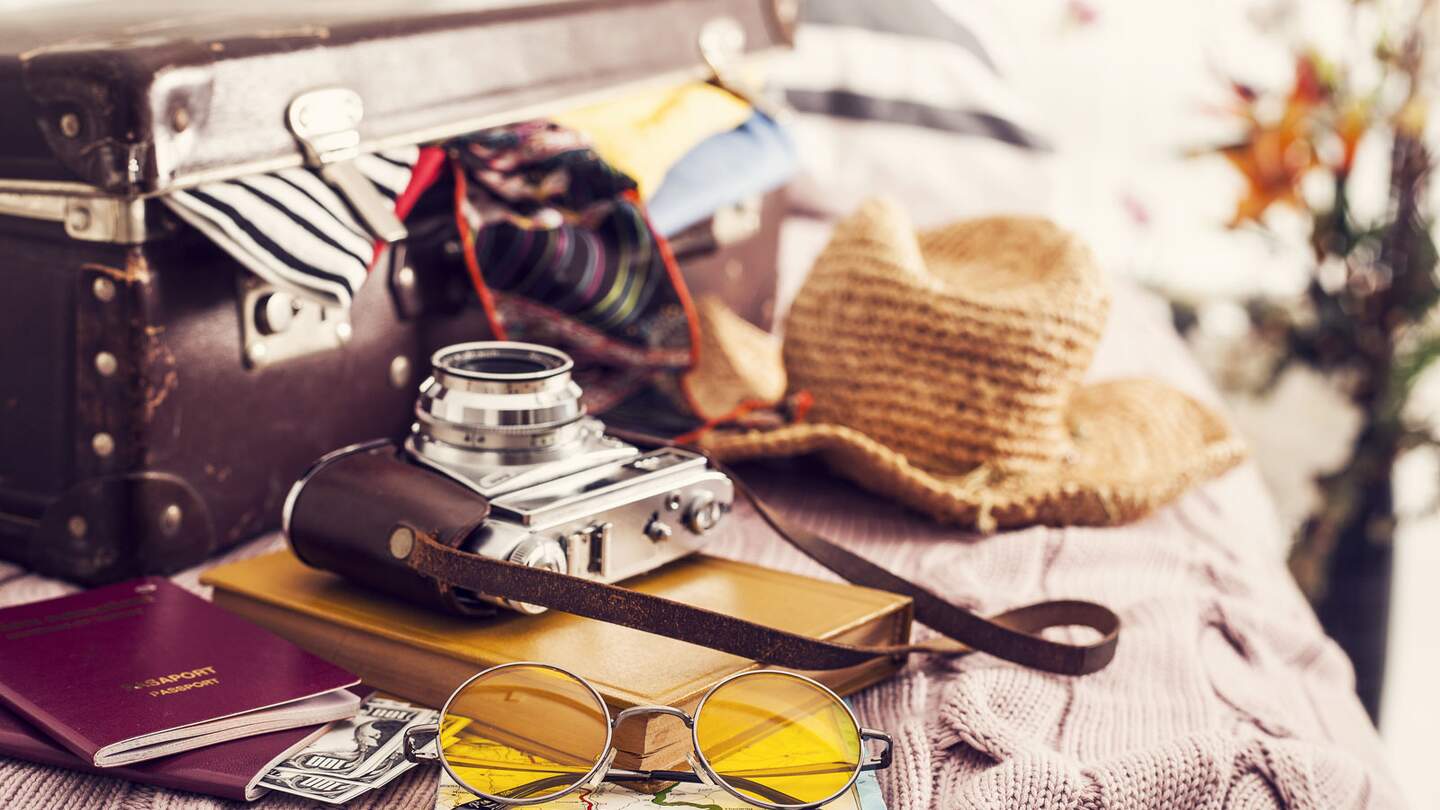 Koffer  liegt gepackt auf einem Bett mit weiteren bereitgelegten Sachen | © Gettyimages.com/seb_ra